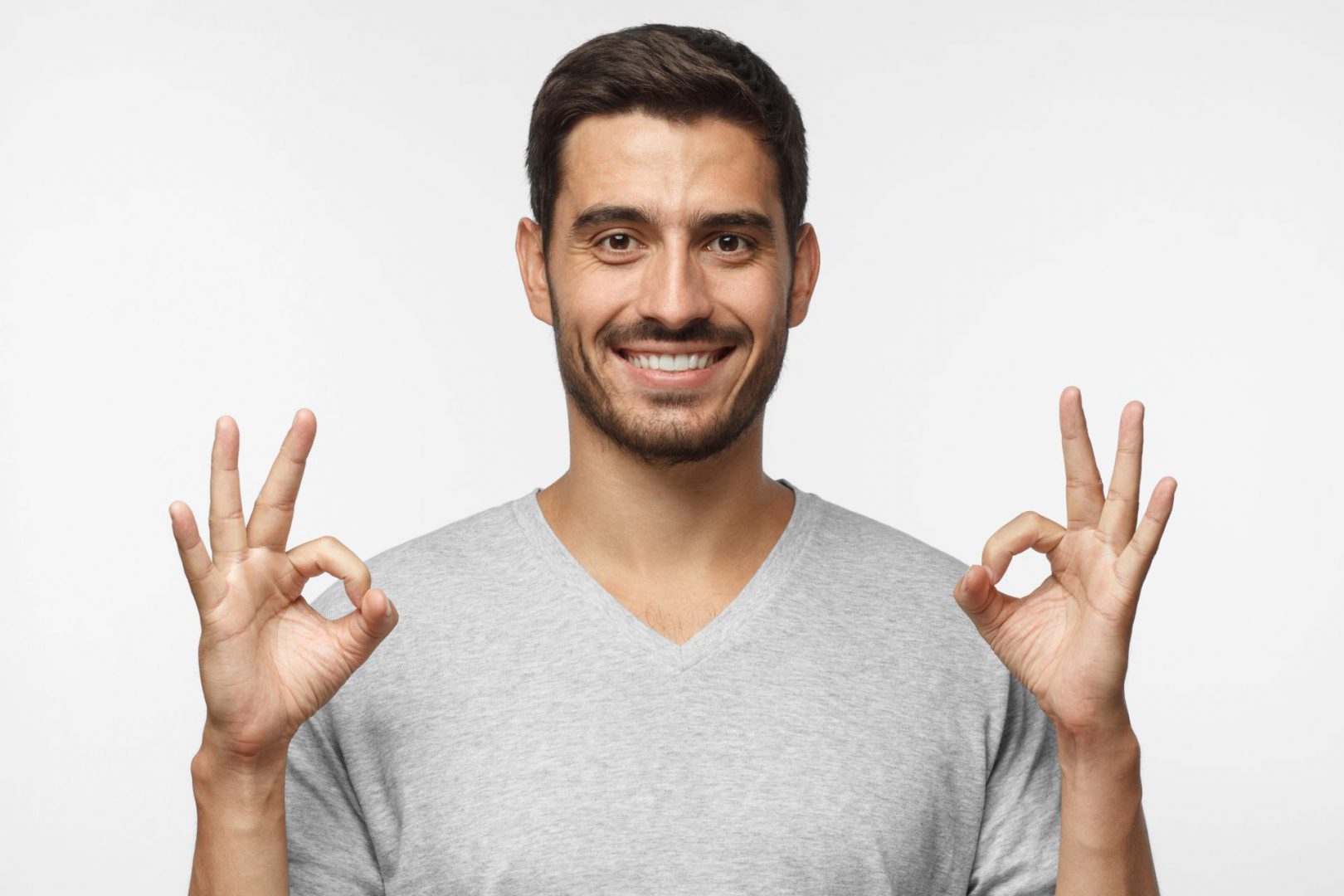 Good looking smiling man showing OK sign with two hands